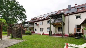 Ein zweistöckiges Haus mit überdachter Terrasse, Holzzaun und Rasengarten.