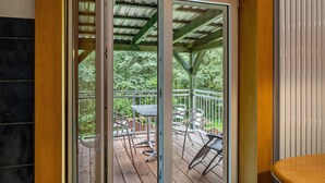 A wooden deck with outdoor furniture, a glass door leading to a covered area, and a white radiator.