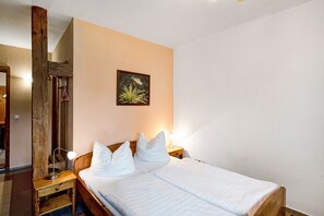 Ein Schlafzimmer mit einem hölzernen Bett, einem Nachttisch, einer Lampe und einem Bild an der Wand.