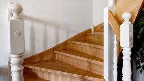 Eine Holztreppe mit weißen Spindeln und einer weißen Wand.