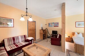 A cozy living room with a sofa, a coffee table, a TV, and a wooden door. - Holiday Apartment Zander with Wi-Fi (Feldberger Seenlandschaft)