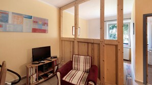 A living room with a television, a sofa, a wooden partition, and a bookshelf.