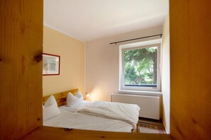 A bedroom with a bed, a window with a view of greenery, and a radiator. - Holiday Apartment Zander with Wi-Fi (Feldberger Seenlandschaft)