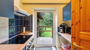 Une cuisine donnant sur un jardin, avec une porte en bois et une petite étagère sur laquelle se trouve un panier.