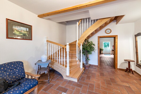 A staircase with wooden railings, a blue patterned sofa, a small table with a checkered tablecloth, and a potted plant.