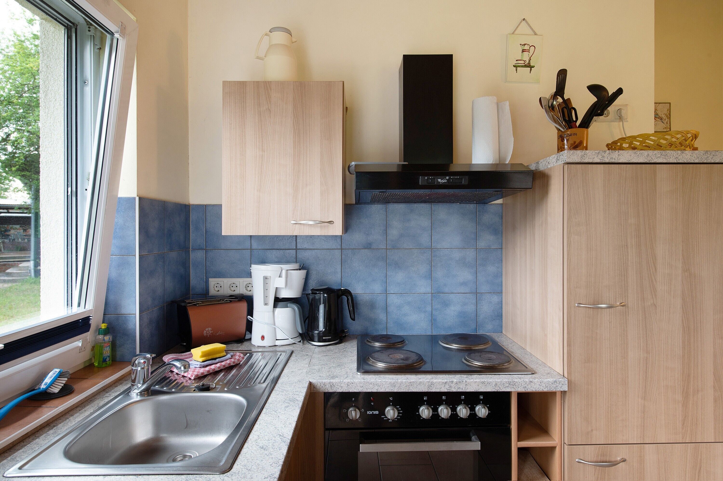 Une cuisine de taille réduite, équipée d’un évier, d’une cuisinière et d’une machine à café.