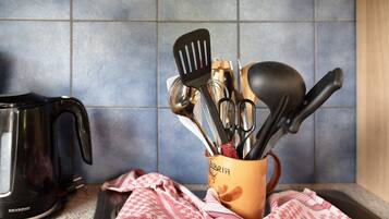 A kitchen counter with a coffee maker, a utensil holder, and a red and white checkered cloth.