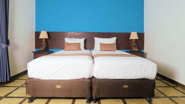 A double bed with two nightstands, a blue accent wall, and a patterned floor. - Attara Heritage Senggigi (Senggigi)