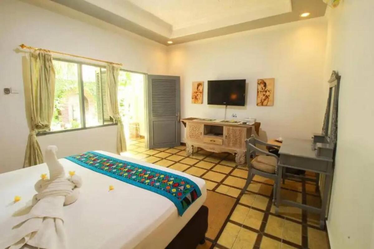A hotel room with a bed, a desk, a television, and a window with curtains.