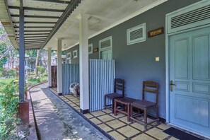 A covered outdoor area with a tiled floor, a row of chairs, and a door with a sign above it. - Attara Heritage Senggigi (Senggigi)