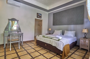 Una camera d'albergo con un letto, una scrivania, uno specchio, un quadro e un pavimento decorato.