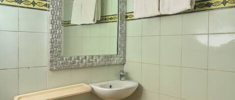 A bathroom with a sink, mirror, and towel rack.
