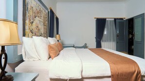 Une chambre d’hôtel avec un lit, une table de chevet, une lampe, un tableau au mur et une porte avec des rideaux.