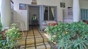 A room with a tiled floor, a window with shutters, a table with chairs, and a red tablecloth. - Attara Heritage Senggigi (Senggigi)