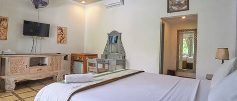 Habitación de hotel con cama, escritorio, televisor y espejo.