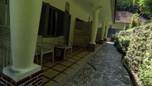 Un espace extérieur abrité, doté d’un sol carrelé, d’un banc et d’une chaise.