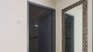 A room with a dining table, a chair, a door, and a mirror with a decorative frame. - Attara Heritage Senggigi (Senggigi)