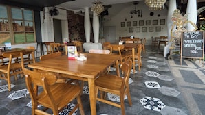A restaurant interior with wooden tables and chairs, a chalkboard sign, and a mural on the wall. - Attara Heritage Senggigi (Senggigi)