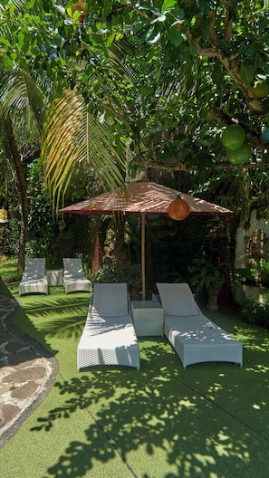 Ein Garten mit Sitzgelegenheit, einer Pergola und üppigem Grün.