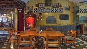 Un restaurant avec des tables et des chaises en bois, un coin bar et un mur décoré de tableaux encadrés.