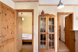 Una habitación de madera con una cama, un aparador con puertas de cristal y una lámpara colgante.