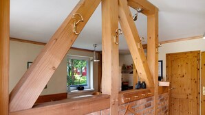 Una estructura de madera con ganchos metálicos, un muro de ladrillo y una puerta de madera.