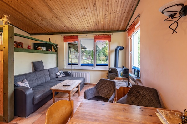 Un salon chaleureux avec un canapé, des fauteuils, une table, une cheminée et une vue par les fenêtres.
