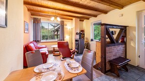 A cozy dining area with a wooden table set for two, a red leather sofa, and a brick fireplace. - Holiday Home 'Ferienhaus Mine Hüsung' with Private Terrace, Shared Garden and Wi-Fi (Feldberger Seenlandschaft)