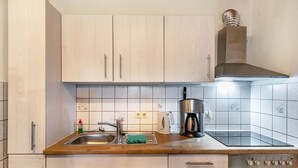 A kitchen with light wood cabinets, a stainless steel range hood, a sink, a kettle, and a coffee maker. - Holiday Home 'Ferienhaus Mine Hüsung' with Private Terrace, Shared Garden and Wi-Fi (Feldberger Seenlandschaft)