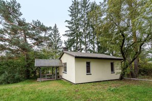 En liten, envåningsbyggnad med ett tak täckt av tegelpannor, omgiven av träd.