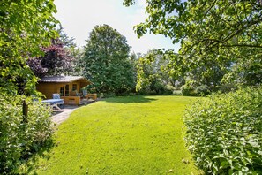 Une cabane en bois avec une pelouse et un espace extérieur aménagé pour s’asseoir.
