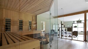 A modern interior with wooden paneling, a glass partition, and a visible kitchen area.