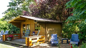 A wooden cabin with a porch, outdoor seating, and a garden.