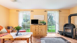 Ein gemütliches Wohnzimmer mit einer Couch, einem Couchtisch aus Holz, einem Fernseher, einer Anrichte und einem Kamin.
