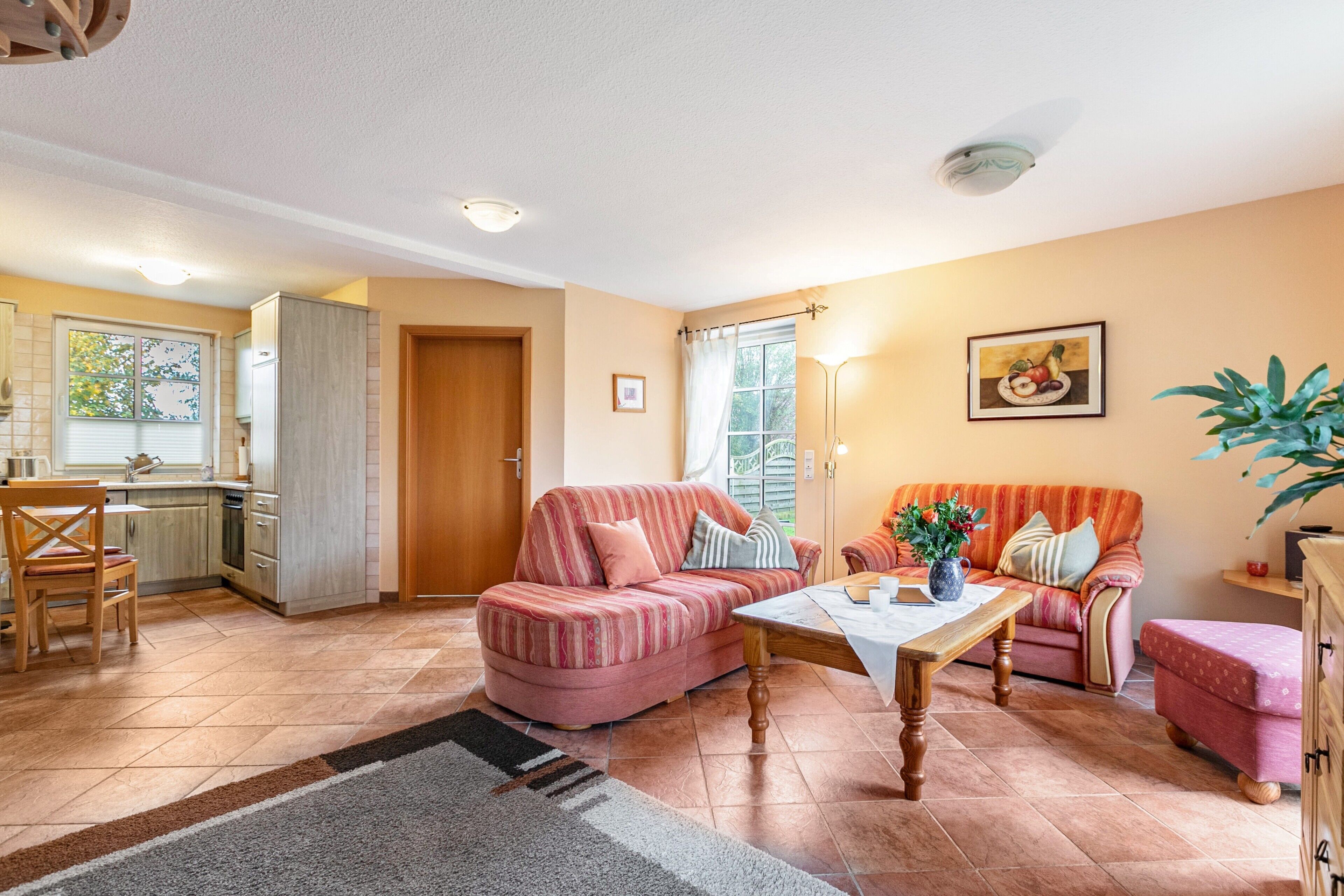 A living room with a sofa, a coffee table, and a dining area with chairs and a table.