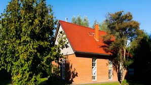 Ein Haus mit rotem Dach, Ziegelaußenwand und gepflegtem Rasen.