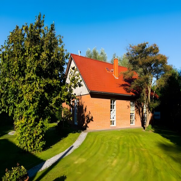A house with a red roof, a brick exterior, and a well-maintained lawn.
