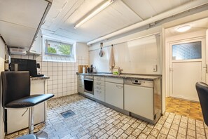 A kitchen with a tiled floor, a sink, a stove, and a chair. - ‘TULIP PATH 3’, holiday & fitter basement flat with heart (Melle)