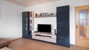 Un salon moderne doté d’un téléviseur à écran plat, d’étagères intégrées et d’une porte coulissante.