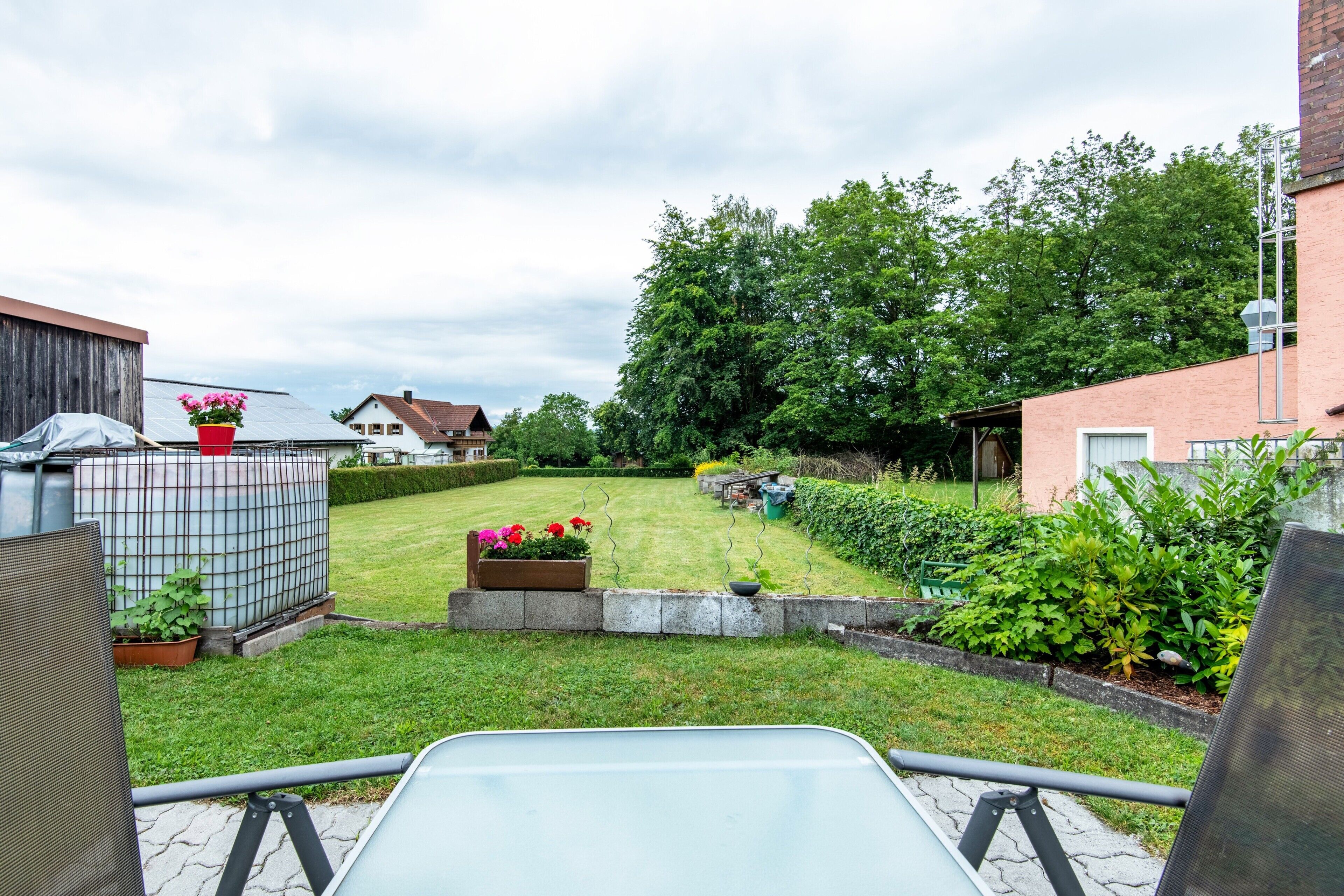 Ein Garten mit Rasen, Holzzaun und einem Metallstuhl.