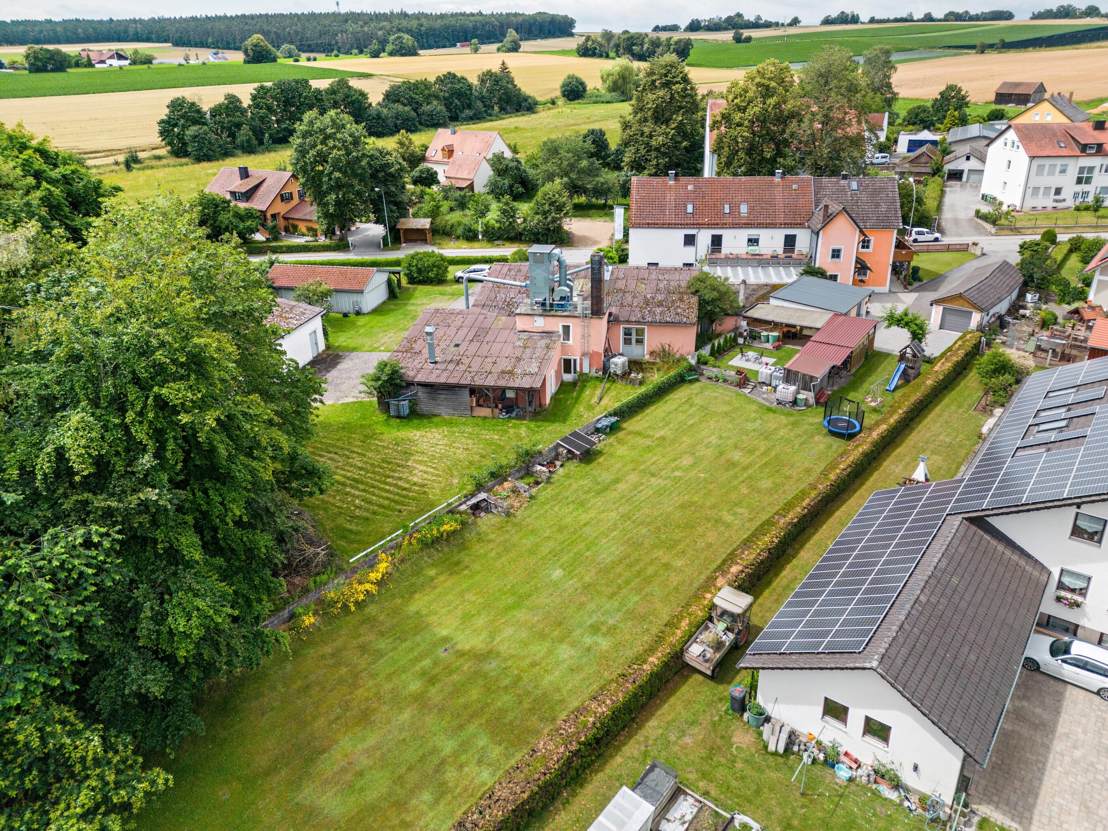 A rural residential area with houses, a green field, and solar panels.