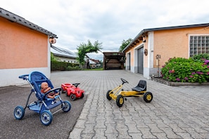 Ein gepflasterter Weg mit einem Kinderwagen, einem roten Spielzeugauto und einem gelben Dreirad.