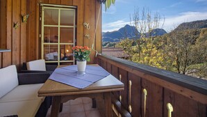 En træbalkon med et bord, stole og en potteplante.