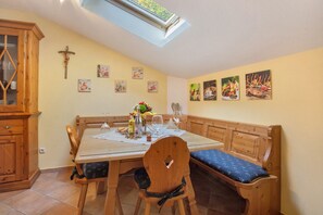 Un espace repas avec une table en bois, des bancs et une lucarne.