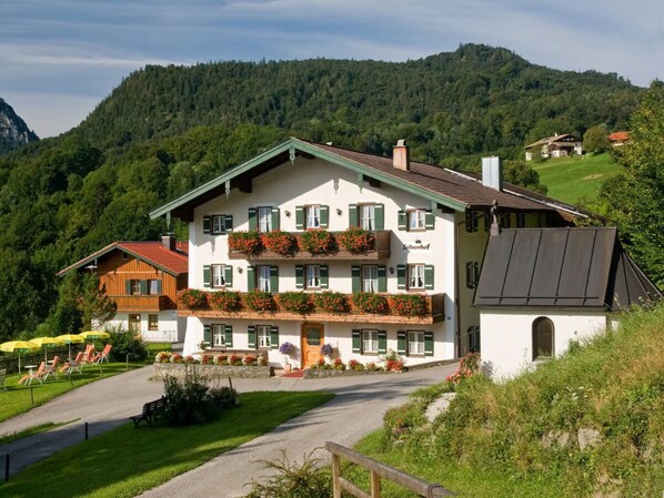 Un immeuble à plusieurs étages doté de balcons, d’une allée pavée et surplombant un paysage montagneux.
