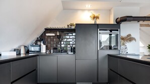 Una cocina moderna con armarios oscuros, horno empotrado y ventana.