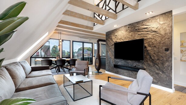 Una sala de estar moderna con una pared de piedra, un televisor de pantalla plana, una chimenea y un comedor con sillas y una mesa.