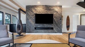 Una sala de estar moderna con una pared de piedra, un televisor montado, una chimenea y dos sofás grises.