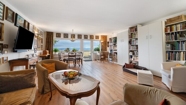 A spacious living room with a large window, a dining area, and a bookshelf. - Apartment 'Rheinblick Am Rheinsteig' with Mountain View, Wi-Fi and Air Conditioning (Urbar)