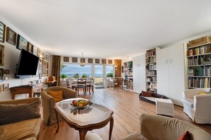Ein geräumiges Wohnzimmer mit großem Fenster, Essbereich und Bücherregal.